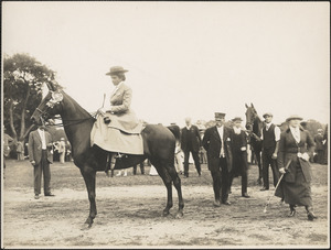 Woman sitting astride a horse in front of a group of people