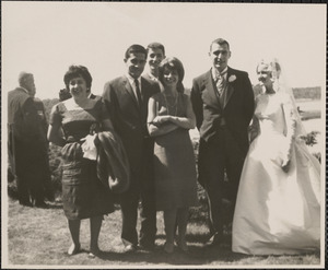 Group portrait of three women including one in a wedding dress and three men