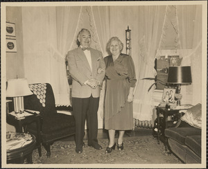 Man and woman posing next to chair