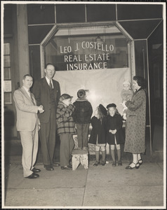 Leo J. Costello shaking the hand of Thomas F. Hughes, the Costello family standing to their right