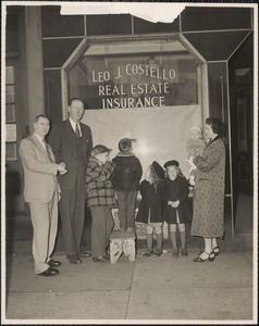 Leo J. Costello shaking the hand of Thomas F. Hughes, the Costello family standing to their right