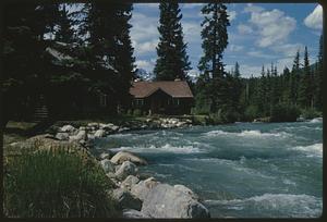Rapids in front of house set among trees, British Columbia