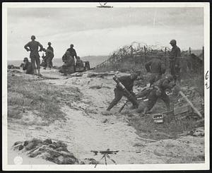 "Goon Gun" on Normandy Beachhead-Half an hour after landing on the coast of France, these members of a Chemical Warfare Battalion go into action with the 4.2 chemical mortar which fired 20 white phosphorous shells a minute at German positions a mile down the Cherbourg peninsula. Fuses for this weapon, dubbed the "goon gun" by doughboys, are manufactured and loaded by New England war workers.