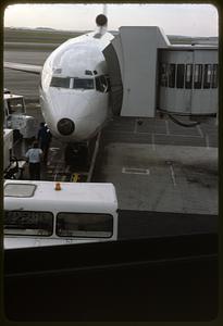 Airplane parked on airport tarmac attached to jet bridge