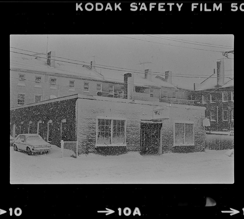 Buildings, cars, and street covered in snow