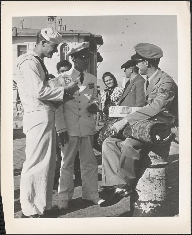 Members of the crew of the heavy cruiser USS Dayton, their shopping completed, wait for the liberty launch at the fleet landing in Izmir, Turkey