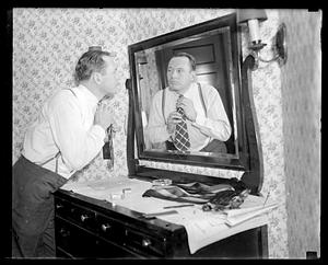A man adjusting his tie, looking in a mirror