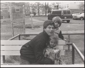 Val Postell holding two children on a bench