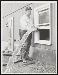 Pumping the Concord River out of his cellar is T. Robert Primmerman of 16 Sheridan Rd., Bedford. Like many of his neighbors, Primmerman had to evacuate his family because of the flood.