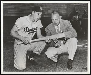 Gil Hodges, Dodgers star, (at left) examines the "business end" of a New York ashwood bat, as Hal Schumacher, ex-Giant pitcher and now vice-president of a New York State bat manufacturing company looks on.