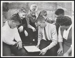 African Numbers game “Kalah” fascinates this group of Melrose students introduced to it during visit to Boston Public Library. Improving their agility with numbers by playing the 7,000-year-old game are, from left, Philip Beauchamp, Richard Kelly, Jeffrey Canada, Frank Mead, Alfred Hammond and Mary Ann DiAngelo. Library is exhibiting game for all visitors.