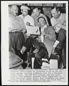 Stanky Meets Red Bird Coaching Staff-- using an unlighted stove in the St. Louis spring training clubhouse here for a footrest Eddie Stanky, new Red Bird manager, has his first meeting with Cardinal coaching staff today. Left to right are: Coach Buzzy Wares, Road Secretary Leo Ward, Pitching Coach Johnny Riddle, Stanky and Coach Mike Ryba.