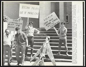 Demonstrators from "Students for Peace in the Middle East," protesting Russian involvement in the Arab-Israeli situation, burn a model of a MIG fighter plane in front of building housing a Soviet photo exhibit.
