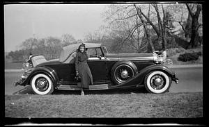 A woman stands in front of a car