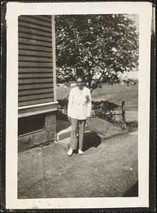 A man stands in front of a tree by a building