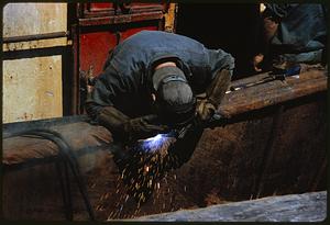Man leaning over to weld