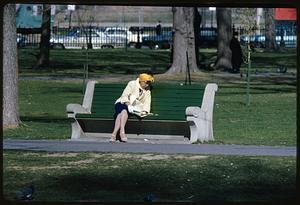 Woman reading newspaper on park bench, Boston Common