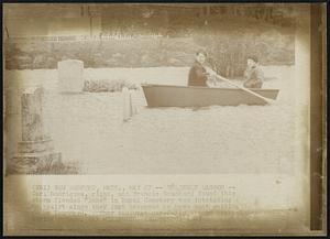 New Bedford, Mass. - Unlikely Lagoon - Carl Rodrigues, right, and Francis Bouchard found this storm flooded "lake" in Rural Cemetery too intriguing to resist since they just happened to have boat waiting to be launched. They maneuver carefully around gravestones during voyage.