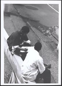 Junior Gabriel (on left) and another young man sitting and writing
