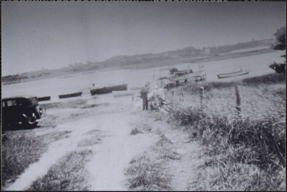 People, boats and automobile at shore