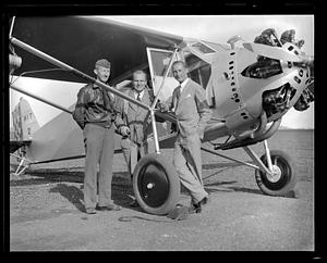 Three unidentified men posing in front of an airplane