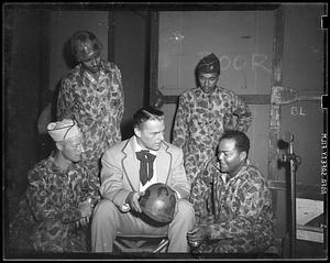 A man holding a helmet sits surrounded by four men in "Jungleers" uniforms