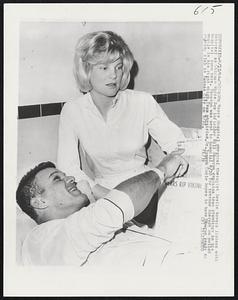 Mercy Hospital physical therapist Leslie Kovacs listens with interest as Chicago White Sox infielder Bill Skowron explains team standings in his hospital room here. Skowron was sent to hospital 9/20 for intense therapy on pulled muscle in his right thigh. Team physician, Dr. Joseph Coyle hopes to have Skowron ready to rejoin club in Kansas City on 9/23.