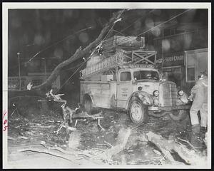For Such Emergencies as this are the Metropolitan Transit Power Dept. trucks on call. This one is shown during storm's height at Washington St. and Vassar St., in Dorchester, where a tree has fallen across wires.