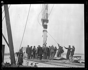A group of men working on the rigging of a sailing ship