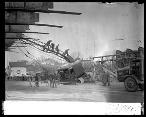 Workers managing a crane which is leaning to one side by some debris