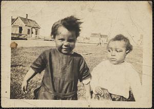 Two toddlers with houses in background