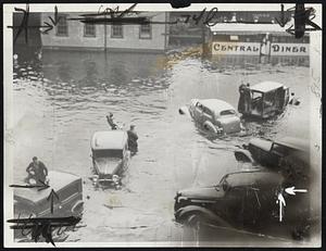 The above photo shows motorists, marooned in the center of downtown Providence, R. I., being rescued.