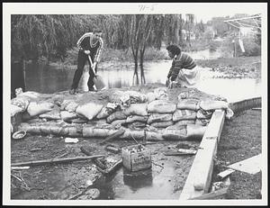 At 38 South St. - Stoneham. Bernd Dekant of Peabody helps Mrs. Louise Kehoe build a dam for her driveway to the garage in the basement of house.