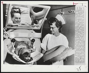 Smiling Through--Mrs. Marry Merry, who is confined in an iron lung at the General Hospital here for polio, smiles happily on her 23rd birthday as Nurse Jennie LeFehr shows her sponge rubber cushion which was presented to her. Mrs. Merry has another birthday coming up, too. Not her own, but that of the baby she is expecting four weeks from now. "It seems like I'm pretty helpless," she smiled through her mirror. " But really, I've an awful lot to do these days..."