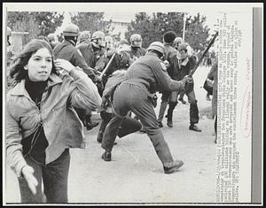 Unidentified girl runs as police subdue demonstrator at trouble-plagued San Francisco State College 1/23. Some 300 police encircled 400 militants holding an illegal rally on the campus, trapped at least 150 demonstrators who were arrested and taken away in patrol wagons. Demonstrators who escaped the encirclement threw rocks, bottles and clubs at police.