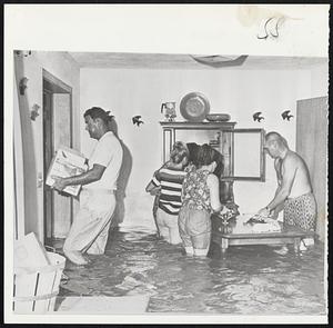 Dora's Work Flood Waters caused by rain from hurricane Dora flood living room in home of Carl Foster (left) of Gainesville, Fla. Other members of the family salvage belongings from the ruined house.