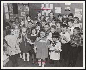 March of Dimes poster child, Jackie Shaughnessy, (left, center) is surrounded by her classmates in the George Frisbee Hoar School in South Boston as class representative Andrea Pano presents a check for donations made by fellow pupils. The money will be used in the fight against birth defects.