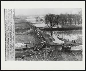 Race Against Flood- Big earth-moving equipment plows through the mud today raising levees in a race to beat rising Missouri River flood waters. A 30-foot crest expected here Thursday would top existing levees.