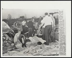 Dunlap, Ind. - Tornado Rescue Scene - The blanket covered woman in center is comforted by a bruised and battered man after they were removed from beneath the debris of house that was leveled by tornado at Dunlap, Ind., yesterday. Rescuers are uncovering other victims in background. About 25 were killed in the Dunlap area.