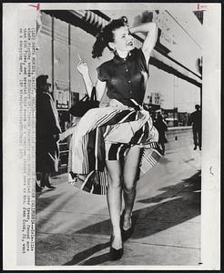 Santa Monice, Calif. - Winds Raise Havoc (?) In Southern California - Gale-like winds ripping across Southern California yesterday and today bowled over trees, fanned more than 200 fires, and created this scene on a downtown street here as Mrs. jean Cook, 21, want on a shopping tour.