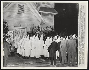 Ku Klux Klan Attends Church Services-Members of the Ku Klux Klan, in full regalia, march into Inman Yards Baptist Church here last night to attend regular Sunday evening services. Many of the hooded figures are women.