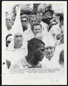 Atlanta, Ga- A Negro youth, one of several attending a K.K.K rally here 6/6, seems undaunted as he stands among uniformed members of the Klan.