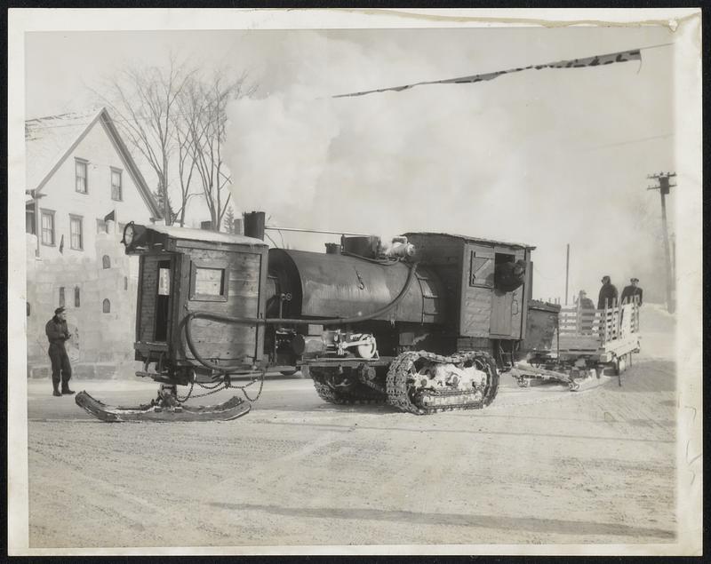 Queer Gear from Yesteryear-To liven the Caribou, Me., winter carnival, a log hauler of the Allagash forests of 40 years ago steams into town. It is believed to have been the last "living" steam log-roller in New England. At left is an ice castle as part of the carnival decorations.