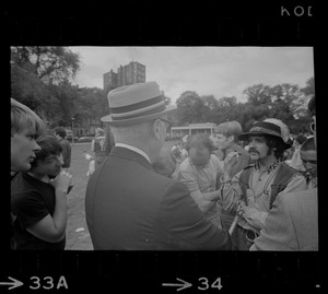 Man with a hat speaking to a group of hippies on the Boston Common
