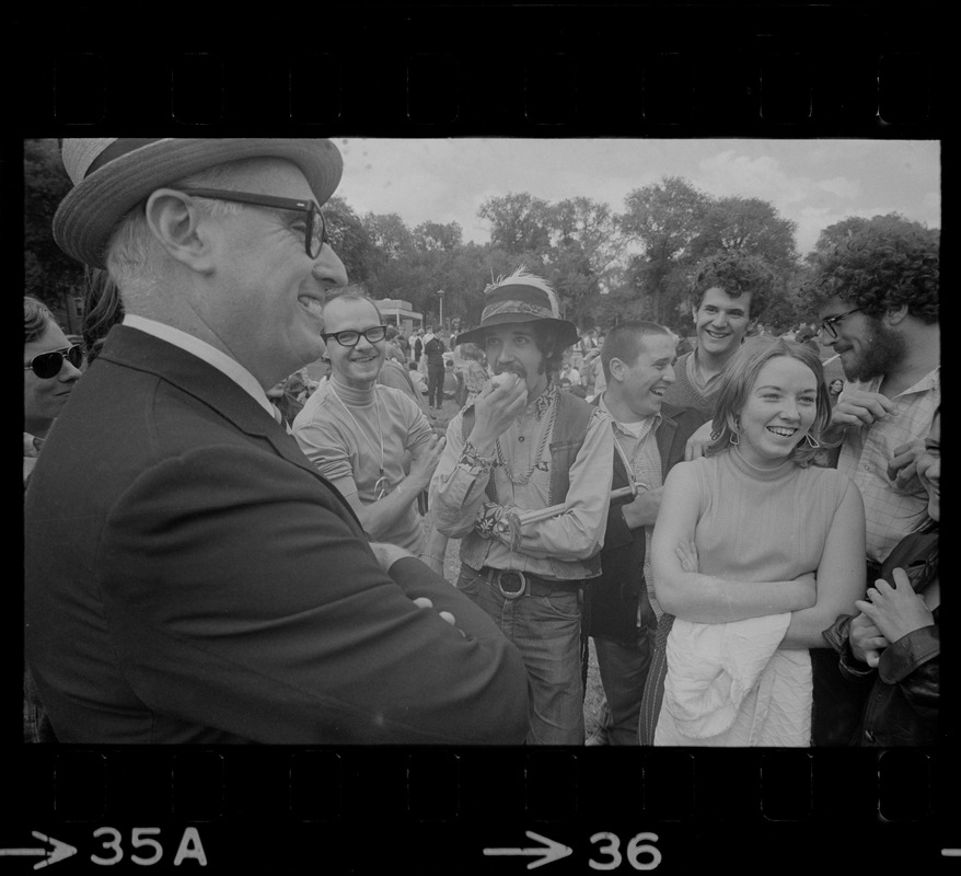 Man with a hat speaking to a group of hippies on the Boston Common