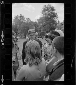 Man with a hat speaking to a group of hippies on the Boston Common