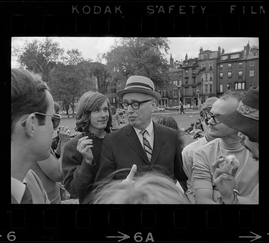 Man with a hat speaking to a group of hippies on the Boston Common