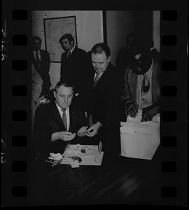 Lt. William J. Gross of State Police Narcotics Unit, seated, and Newton police chief William Quinn, standing center, inspecting items with others