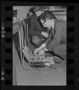 Titicut Follies' hearing taped - Timothy Asch, (right), Cambridge, turns over rolls of film and tape recording to Sgt.-at-Arms John J. Cavanaugh, after it was discovered the "Titicut Follies" hearing at the State House was being recorded