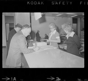 Teddy Green, reformed bank robber, filling out questionnaire while election clerks look on